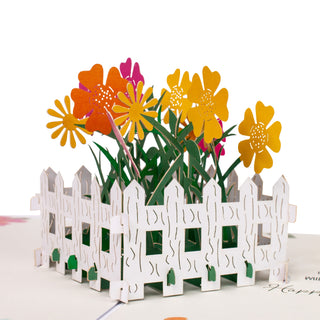 Front view of the colorful flower garden surrounded by a white fence inside the flower garden birthday pop-up card.