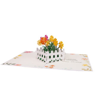 Fully open flower garden birthday pop-up card with the colorful flower garden surrounded by a white fence and printed greeting.