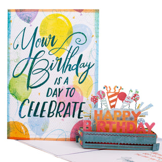 Open happy birthday party pop-up card showing the colorful Happy Birthday party decorations, balloons, and garlands at an angle.